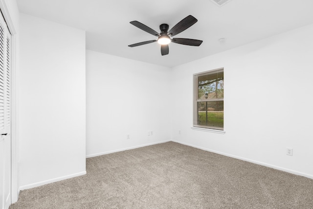 spare room featuring carpet floors, a ceiling fan, and baseboards