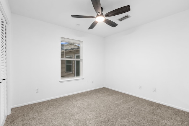 empty room with carpet floors, visible vents, a ceiling fan, and baseboards