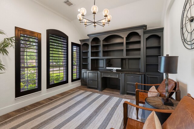 office space with visible vents, vaulted ceiling, built in desk, an inviting chandelier, and light wood-style flooring