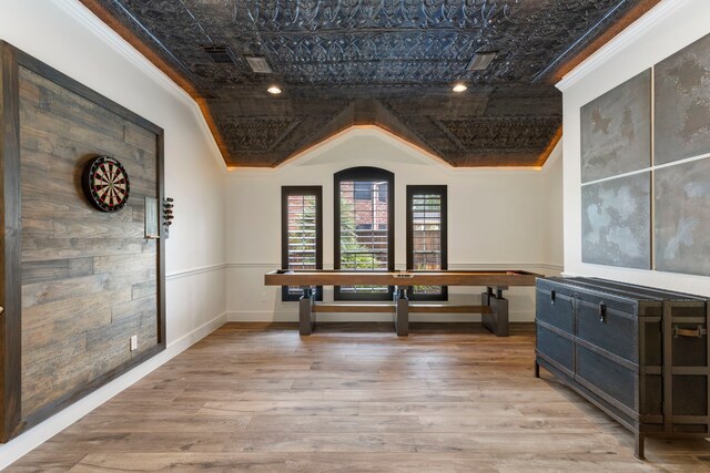 interior space featuring crown molding, baseboards, an ornate ceiling, and wood finished floors