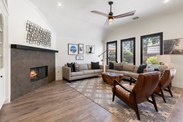 living room with recessed lighting, wood finished floors, vaulted ceiling, a tile fireplace, and visible vents