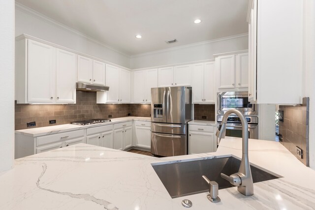 kitchen with white cabinets, appliances with stainless steel finishes, backsplash, under cabinet range hood, and visible vents