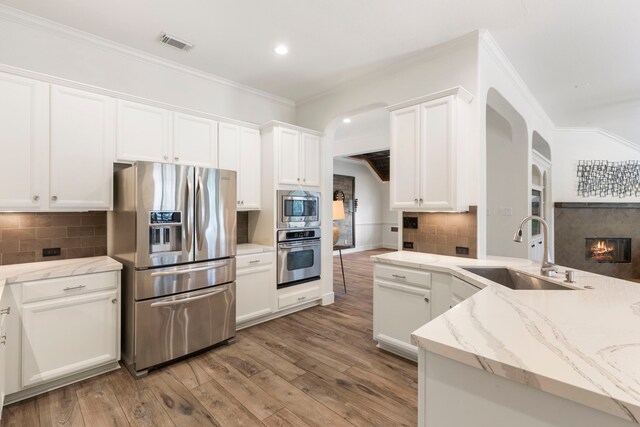 kitchen featuring stainless steel appliances, arched walkways, visible vents, and a sink