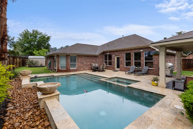 view of pool with a fenced backyard, a patio, a pool with connected hot tub, and grilling area