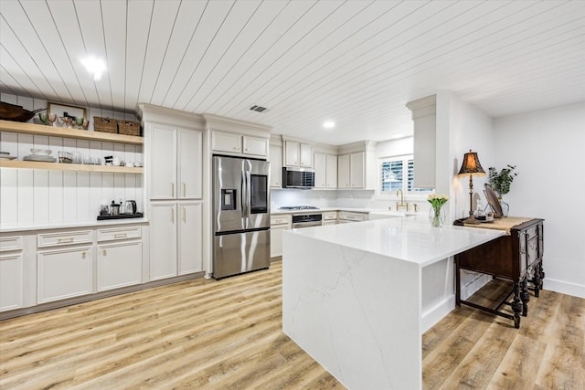 kitchen with light wood-style flooring, a sink, a kitchen bar, and appliances with stainless steel finishes