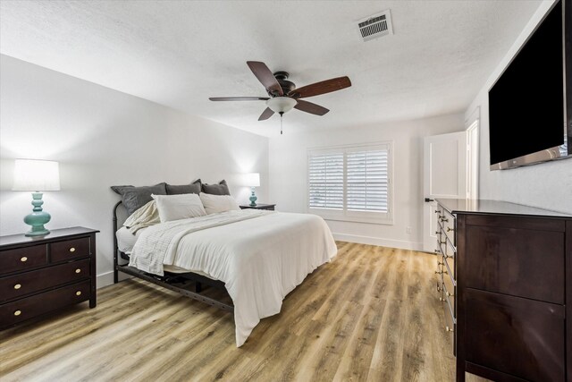 bedroom with ceiling fan, baseboards, visible vents, and light wood-type flooring