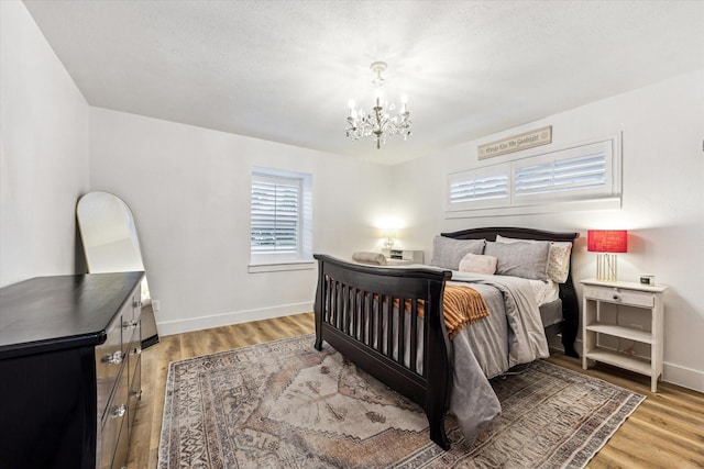 bedroom with light wood-type flooring, baseboards, and a notable chandelier