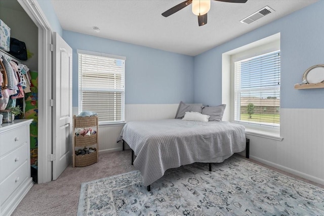 8804 Ute Creek Ln, Magnolia, TX 77354 - carpeted bedroom with ceiling fan, visible vents, wainscoting, and multiple windows