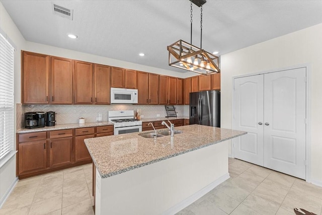 8804 Ute Creek Ln, Magnolia, TX 77354 - kitchen with decorative backsplash, a sink, visible vents, white appliances, and brown cabinetry