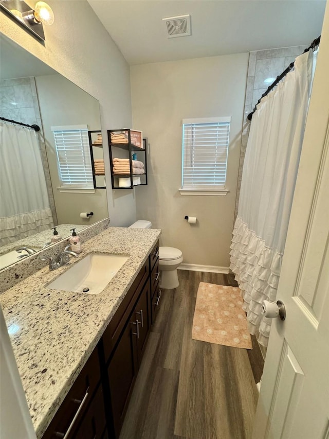 bathroom featuring toilet, visible vents, wood finished floors, a shower with shower curtain, and vanity
