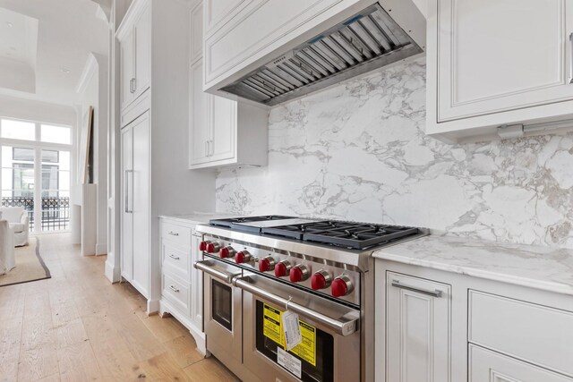 kitchen featuring white cabinetry, custom exhaust hood, tasteful backsplash, and double oven range