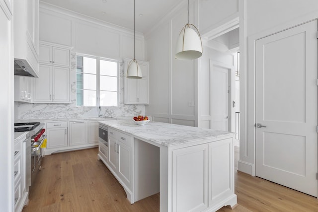 kitchen featuring white cabinets, light wood-style flooring, range with two ovens, crown molding, and a kitchen island