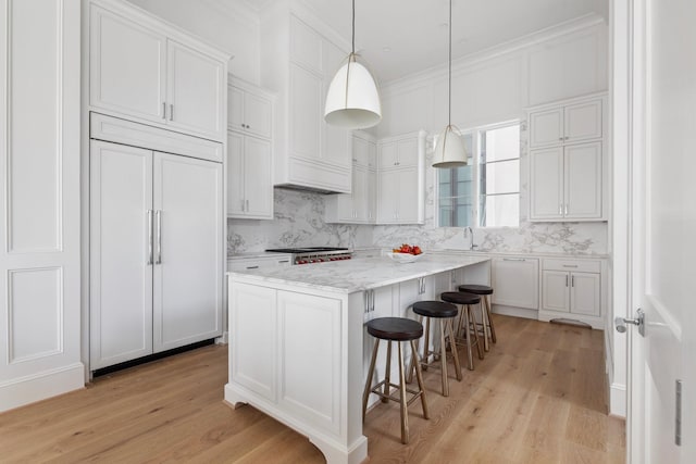 kitchen featuring light wood-type flooring, a center island, paneled fridge, and decorative backsplash