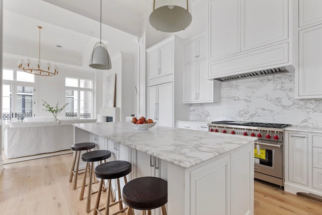 kitchen featuring white cabinets, high end appliances, light wood-style floors, and decorative backsplash