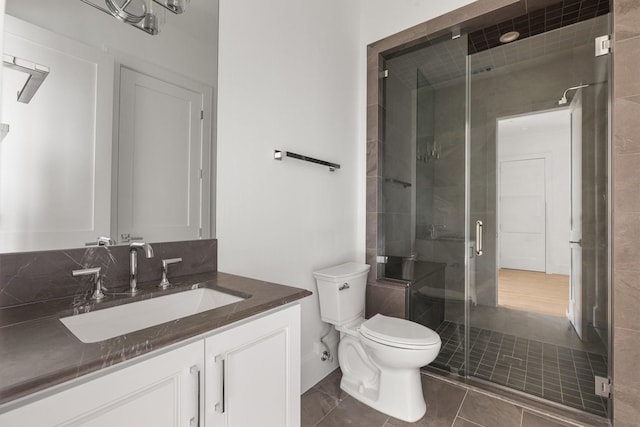 full bath featuring a stall shower, tile patterned floors, vanity, and toilet