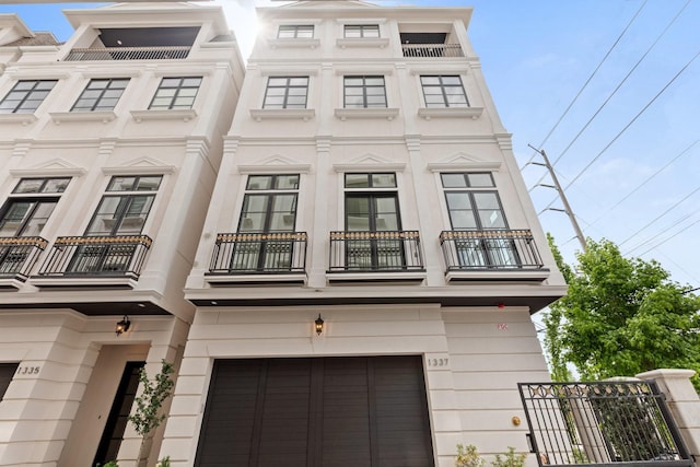 view of front facade featuring fence, a balcony, and a garage