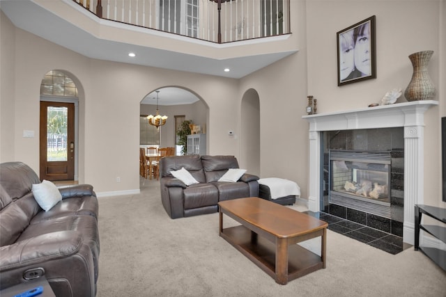 11409 E Zoe Loop Dr, Montgomery, TX 77316 - carpeted living area with a chandelier, a towering ceiling, a tile fireplace, arched walkways, and baseboards