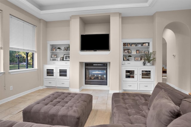 11409 E Zoe Loop Dr, Montgomery, TX 77316 - living room featuring a glass covered fireplace, light tile patterned floors, arched walkways, built in features, and ornamental molding