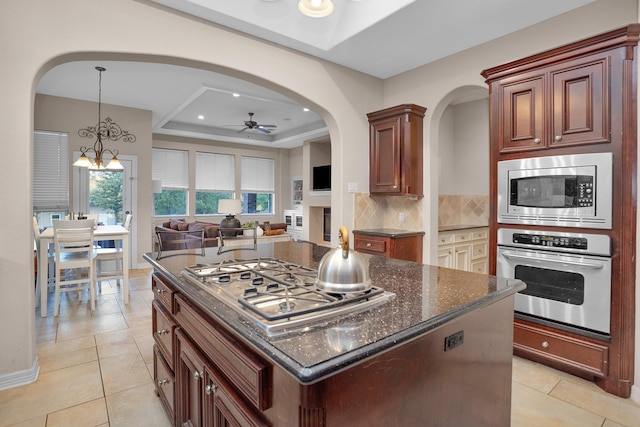 11409 E Zoe Loop Dr, Montgomery, TX 77316 - kitchen with stainless steel appliances, a tray ceiling, a ceiling fan, open floor plan, and backsplash