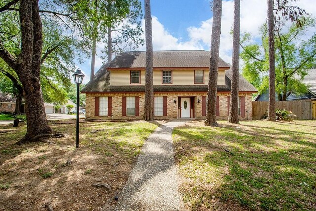 1103 Suwanee Ln, Houston, TX 77090 - view of front of home with fence, a shingled roof, a front lawn, and brick siding
