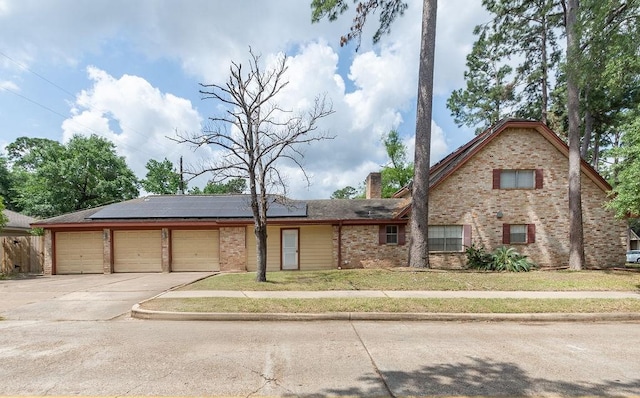 1103 Suwanee Ln, Houston, TX 77090 - view of front of property with solar panels, a chimney, concrete driveway, brick siding, and an attached garage