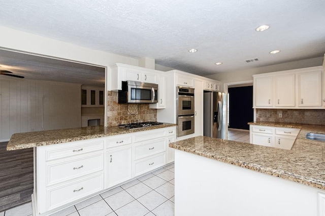 1103 Suwanee Ln, Houston, TX 77090 - kitchen with a peninsula, tasteful backsplash, visible vents, and appliances with stainless steel finishes