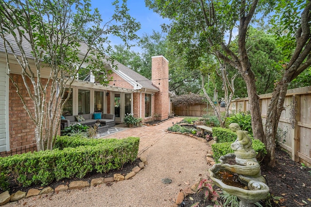 back of house with an outdoor living space, a chimney, a patio area, brick siding, and a fenced backyard