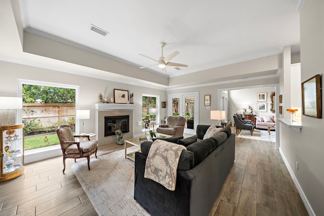 living area with visible vents, ceiling fan, dark wood-type flooring, a raised ceiling, and a tile fireplace