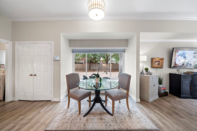 dining room with crown molding, baseboards, washer / dryer, and light wood-type flooring