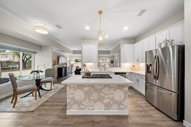 kitchen with visible vents, gas stovetop, light countertops, stainless steel fridge, and white cabinetry