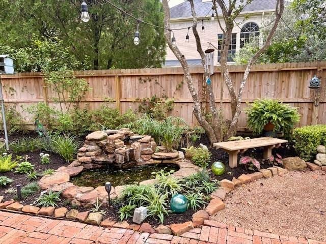 view of yard featuring fence and a garden pond