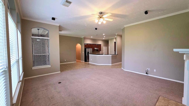 unfurnished living room with visible vents, arched walkways, a wealth of natural light, and ceiling fan