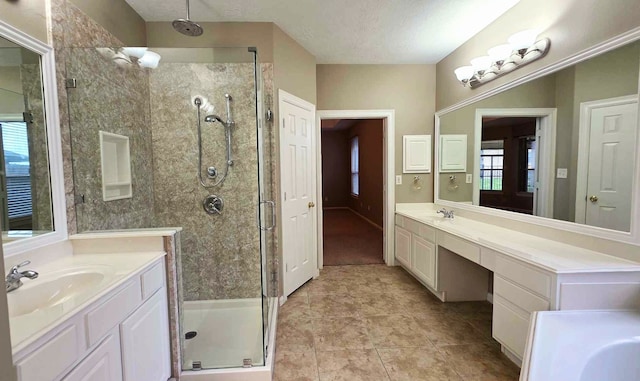full bathroom with a textured ceiling, a sink, a stall shower, two vanities, and tile patterned floors