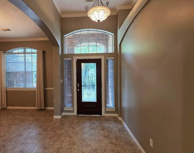 entryway with tile patterned flooring, visible vents, baseboards, ornamental molding, and arched walkways