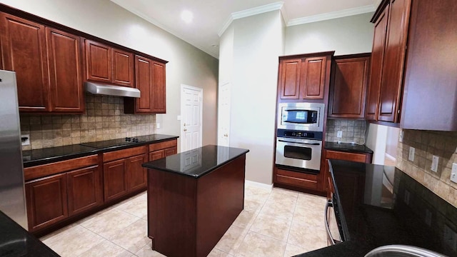 kitchen featuring appliances with stainless steel finishes, a center island, under cabinet range hood, ornamental molding, and backsplash