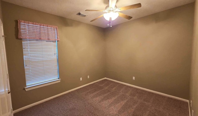 carpeted spare room with baseboards, visible vents, and ceiling fan