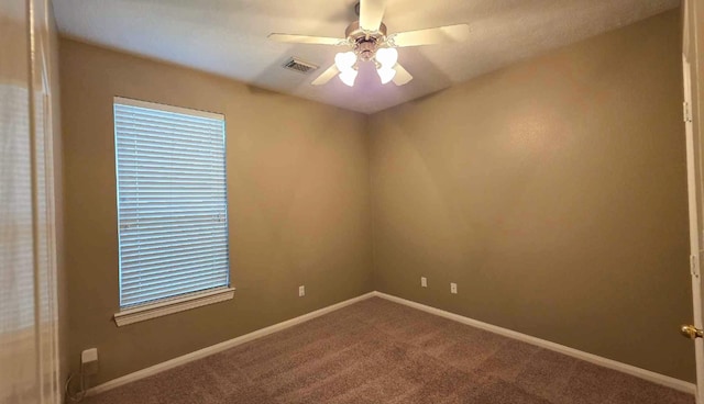 empty room featuring baseboards, visible vents, ceiling fan, and carpet
