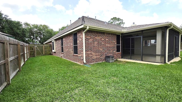 back of property featuring a yard, a sunroom, brick siding, and a fenced backyard