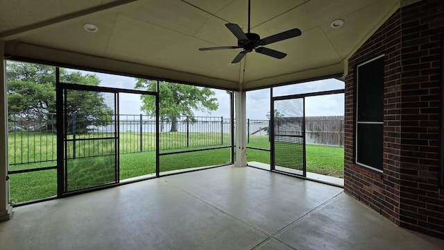 unfurnished sunroom featuring a ceiling fan and a water view