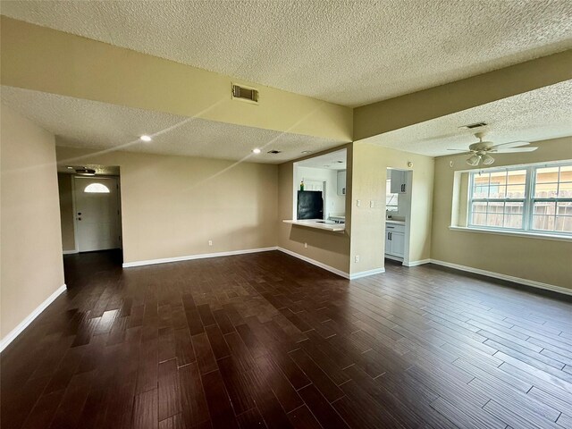 8818 Fern Valley Dr, Houston, TX 77044 - unfurnished living room with a textured ceiling, dark wood-type flooring, ceiling fan, and baseboards