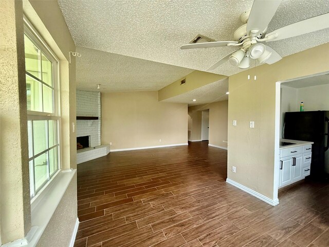 8818 Fern Valley Dr, Houston, TX 77044 - unfurnished living room with a textured ceiling, a ceiling fan, wood finished floors, baseboards, and a fireplace