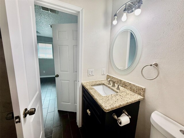 8818 Fern Valley Dr, Houston, TX 77044 - half bathroom with toilet, vanity, a textured ceiling, and wood tiled floors