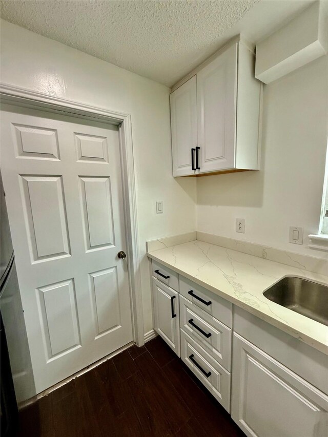 8818 Fern Valley Dr, Houston, TX 77044 - kitchen featuring dark wood finished floors, a textured ceiling, white cabinets, and light stone counters
