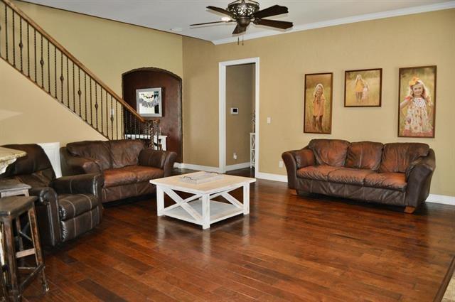 living area with stairway, a ceiling fan, wood finished floors, arched walkways, and ornamental molding
