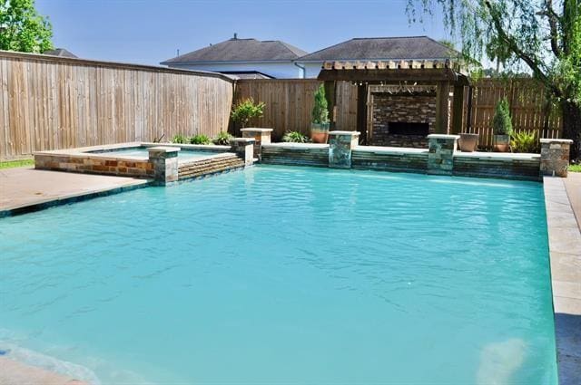 view of swimming pool with a fenced backyard and a pool with connected hot tub