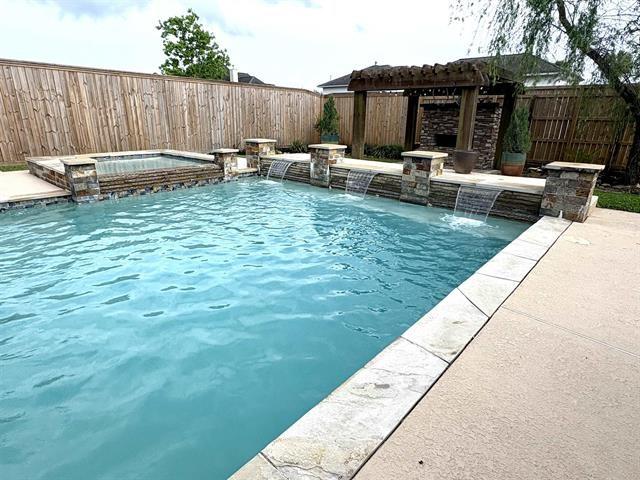 view of swimming pool featuring a patio area, a fenced backyard, a pool with connected hot tub, and a pergola