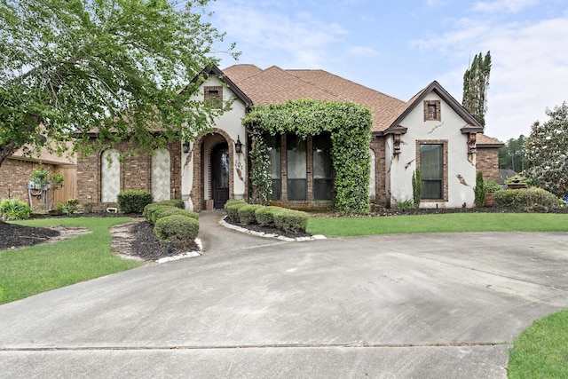 101 Sir Cameron, Lumberton, TX 77657 - tudor home featuring stucco siding, brick siding, a front yard, and roof with shingles