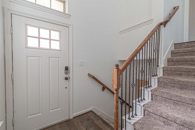 foyer with dark wood-type flooring, stairs, and baseboards