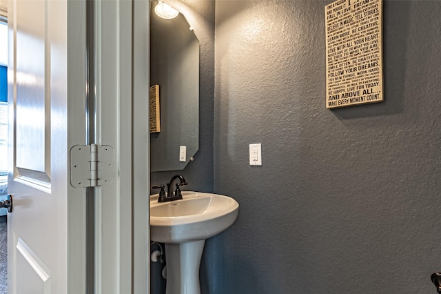 bathroom featuring a textured wall and a sink