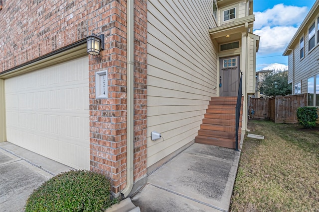 doorway to property with brick siding, a yard, a garage, and fence